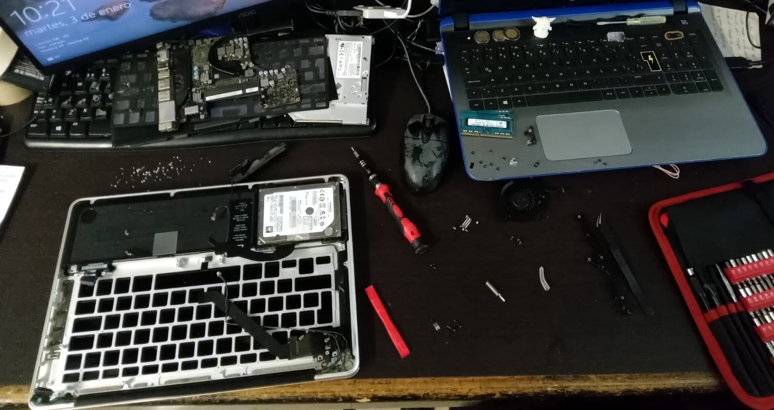 Taller de NexusTI en Cancún con laptops desarmadas en reparación y herramientas de precisión